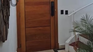 Una puerta de madera con manija, una escalera con barandilla y una planta en maceta.