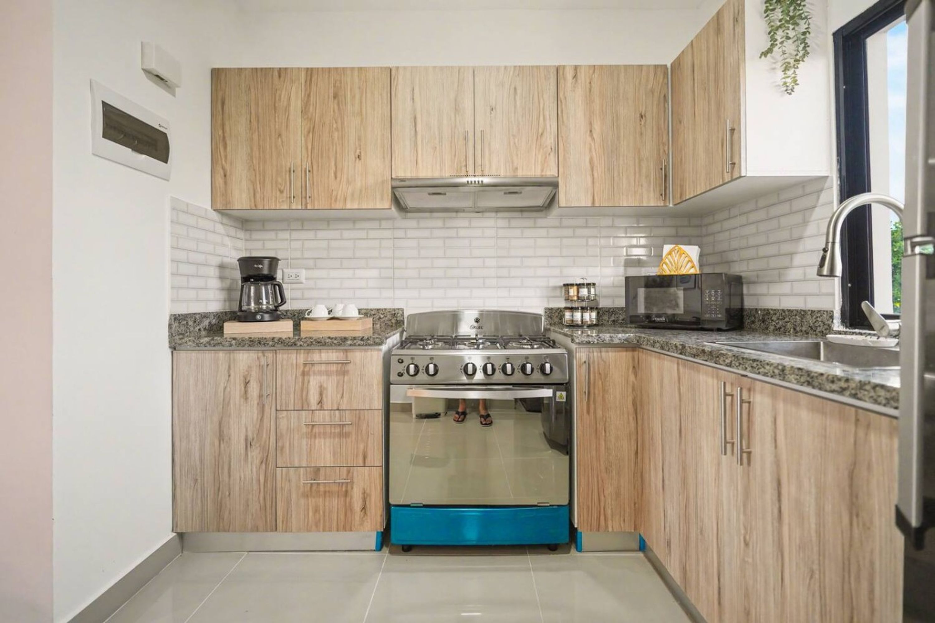 Una cocina compacta con armarios de madera, estufa a gas, microondas y pileta.