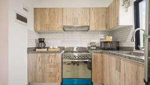 A compact kitchen with wooden cabinets, a gas stove, a microwave, and a sink. - Modern 2BR Pool 5 Min to Coco Bongo Downtown (Punta Cana)