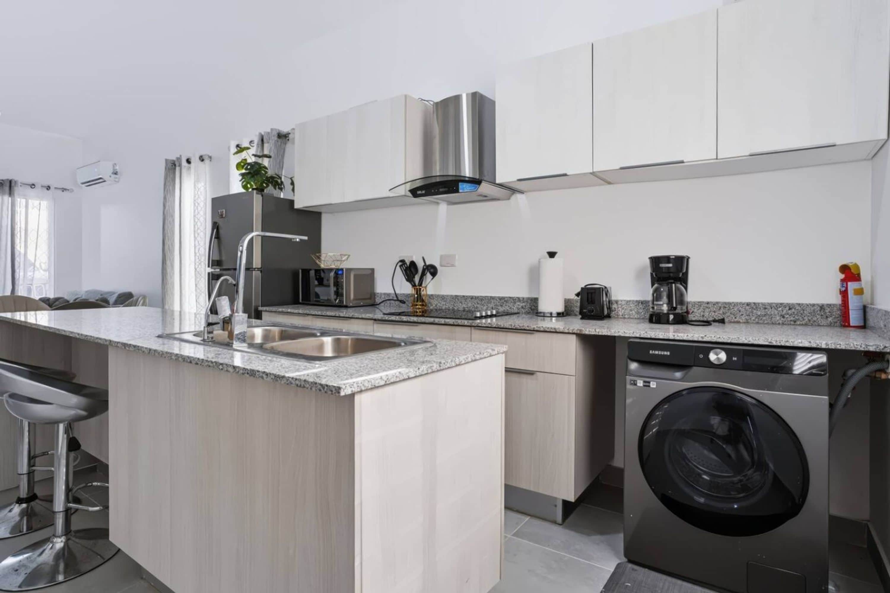A modern kitchen with a built-in dishwasher, a coffee maker, and a washing machine.