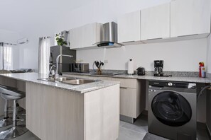 A modern kitchen with a built-in dishwasher, a coffee maker, and a washing machine.
