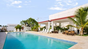 Una piscina con sillas de descanso y un área de estar techada.