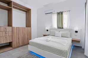 Un dormitori modern amb un llit, un armari, una tauleta de nit i un aparell d'aire condicionat.
