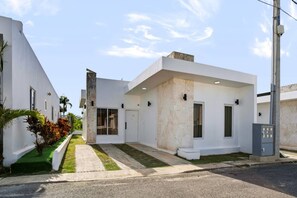 A modern two-story residential building with a flat roof, large windows, and a small front yard with a palm tree. - Spacious 3BR Home Pool Macao Beach (Punta Cana)