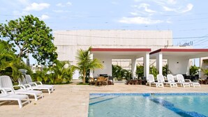 Una piscina con sillones de descanso y una zona de estar cubierta.