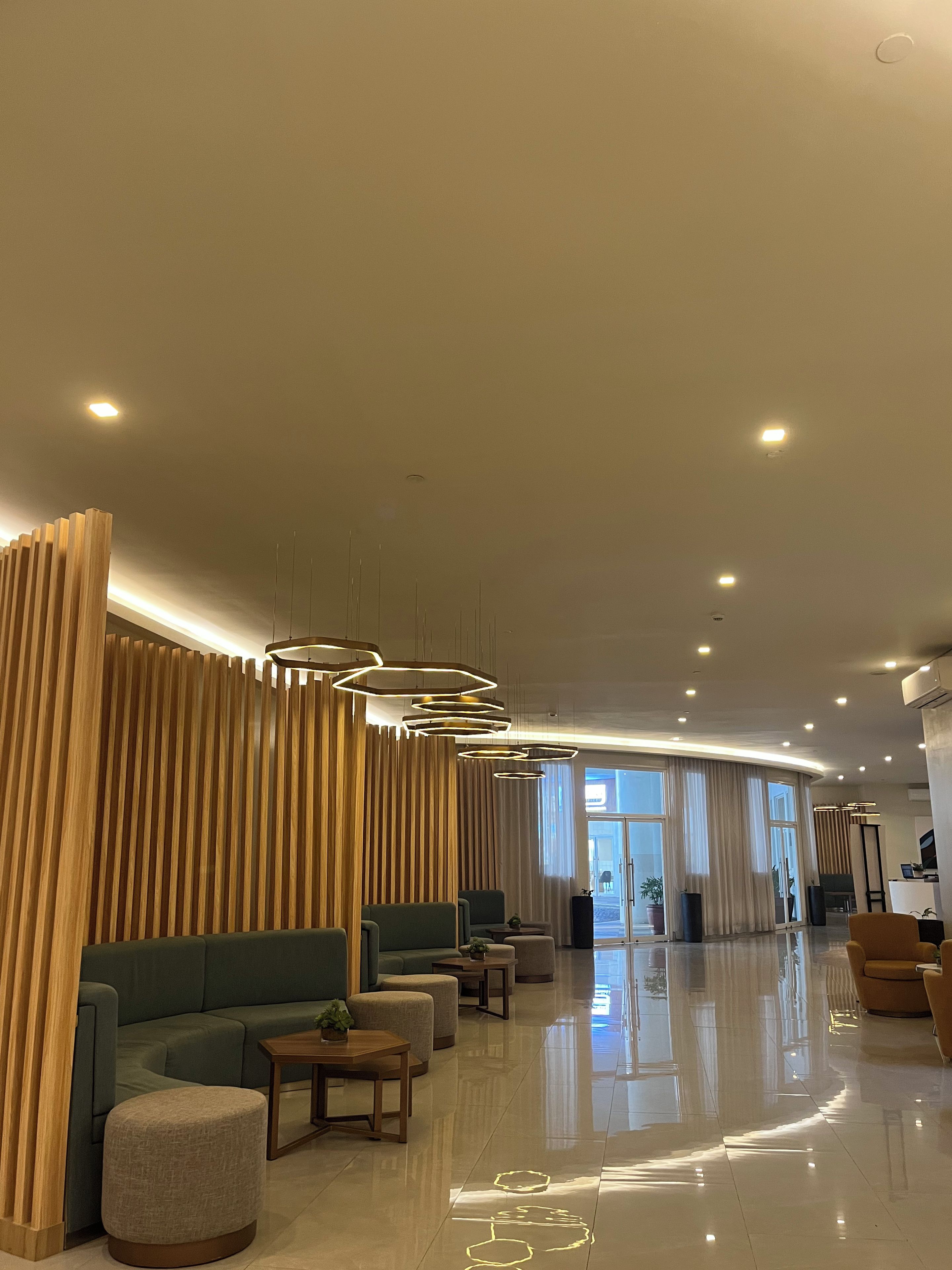 A modern lobby with a curved seating area, recessed lighting, and a large window.