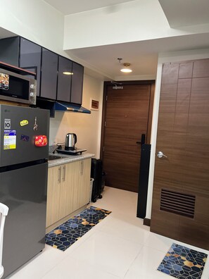 A compact kitchen with a refrigerator, microwave, and a coffee maker on the counter.