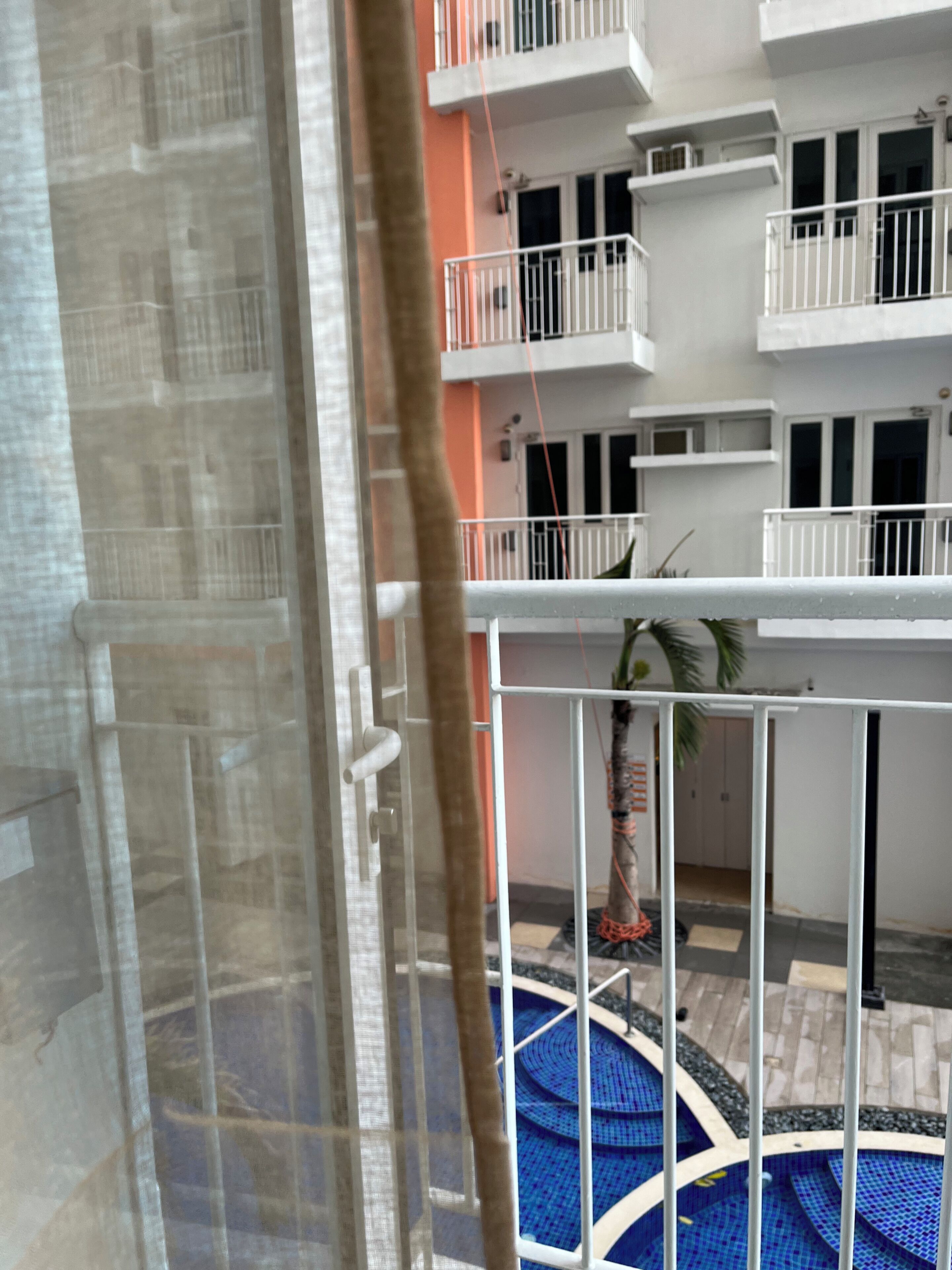 Een uitzicht op een woongebouw met balkons, een zwembad en een deur met een metalen poort.