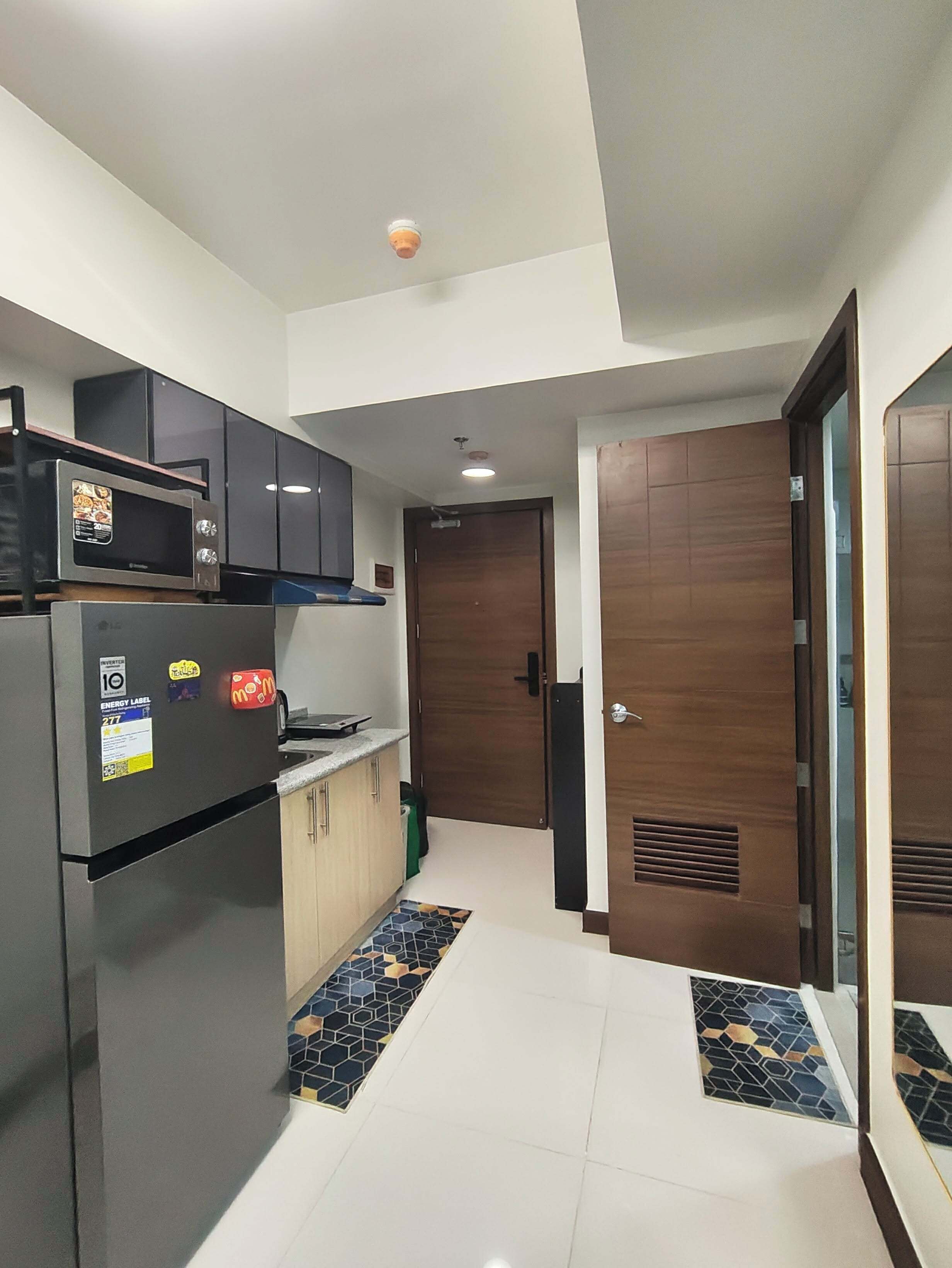 A compact kitchen with a refrigerator, microwave, and wooden cabinets.
