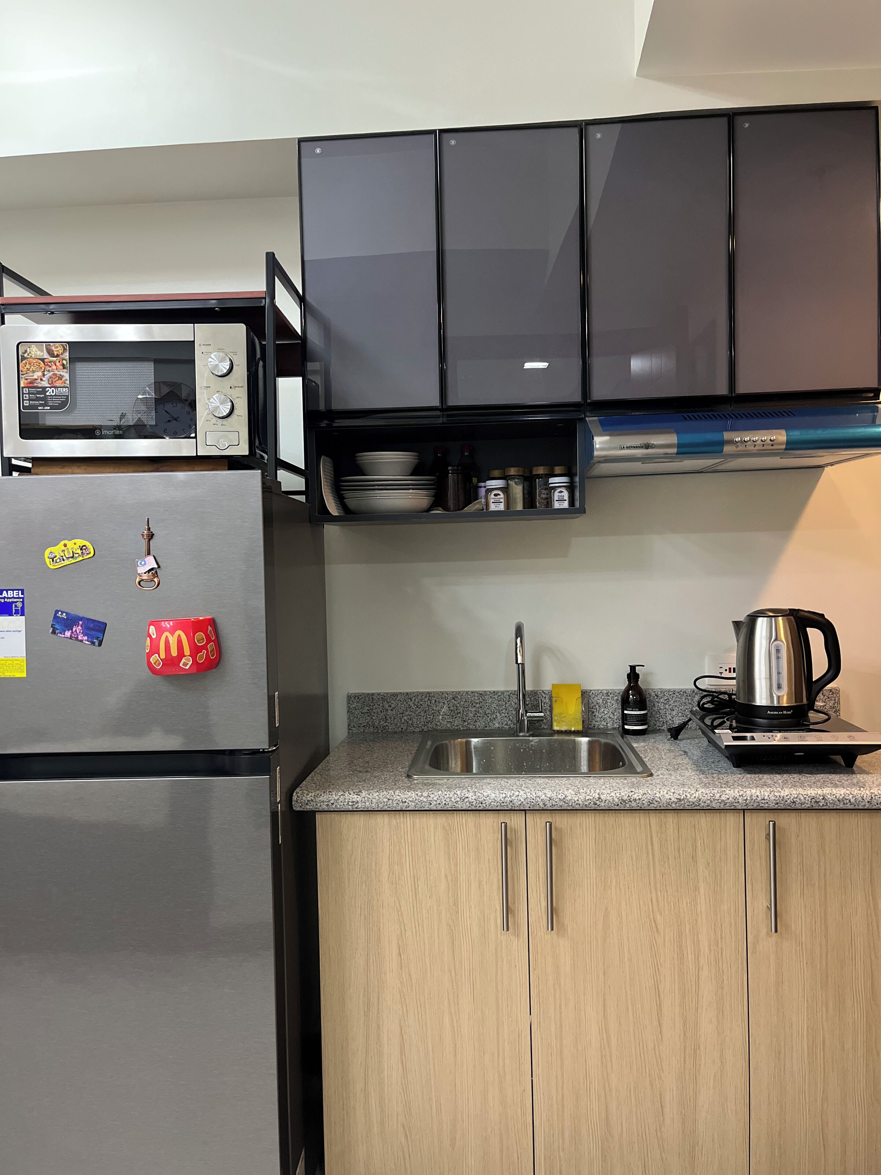 Eine Küche mit Einbau-Mikrowelle, Edelstahl-Kühlschrank, Spüle und Kaffeemaschine.