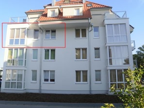 Ein mehrstöckiges Wohngebäude mit flachem Dach und weißen Außenwänden.