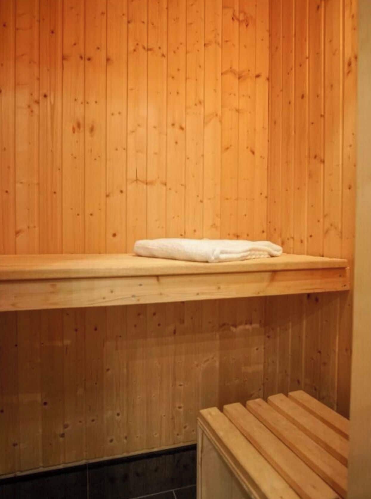 Un sauna avec des murs en bois, un banc et une serviette posée sur le banc.