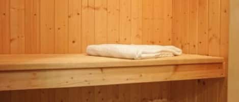 Un cuarto de sauna con paredes de madera, un banco y una toalla sobre el banco.