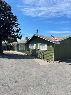 A green single-story building with a sloped roof, a visible chimney, and a flagpole with an American flag. - Sequim and Sun and Fun (Sequim)