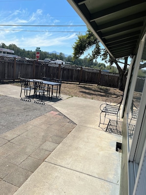 A patio area with a table and chairs, a wooden fence, and a stop sign in the background. - Sequim and Sun and Fun (Sequim)