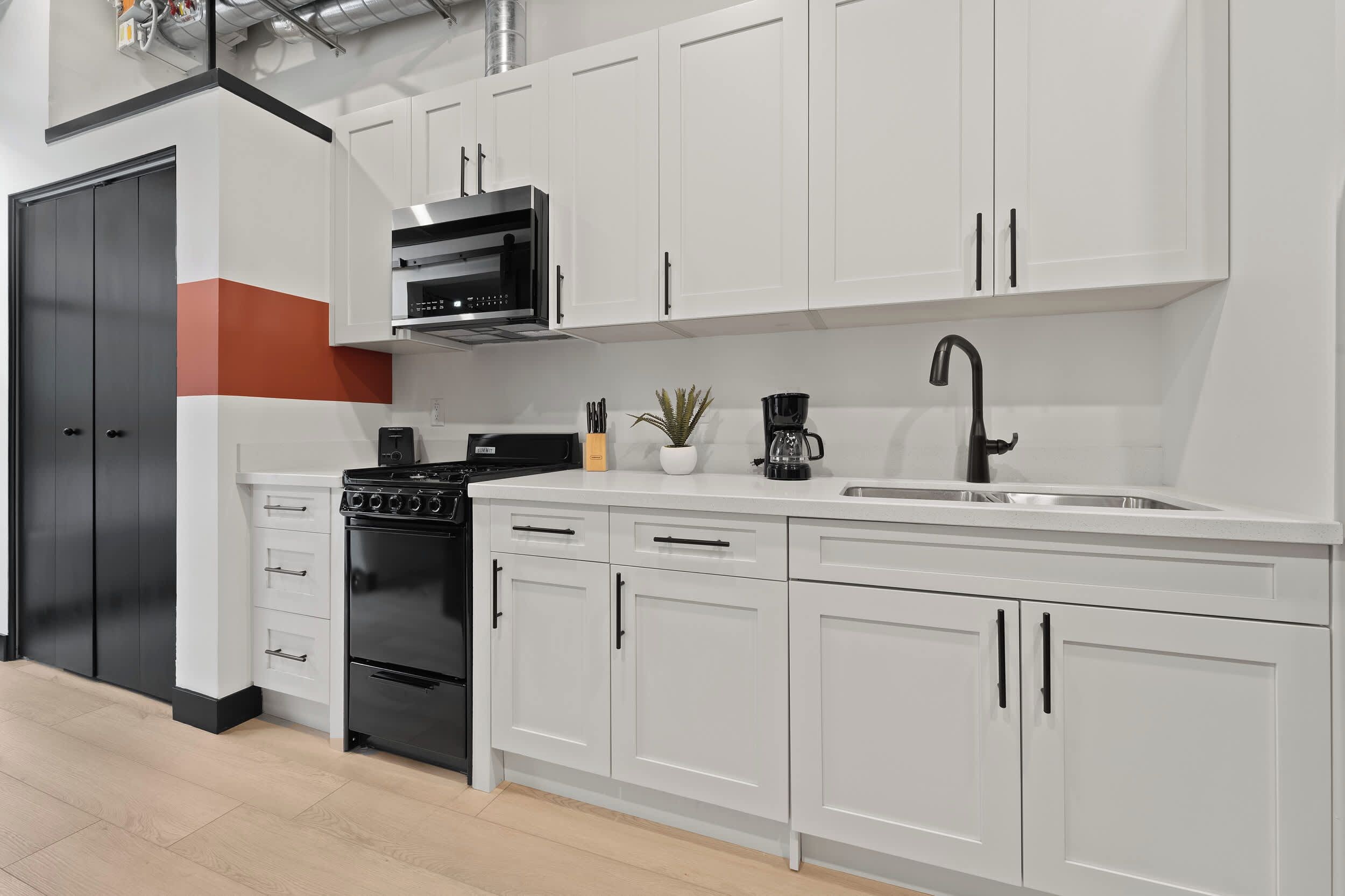 Een moderne keuken met witte kasten, een zwart fornuis en een roestvrijstalen spoelbak.