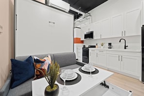 A modern kitchen with white cabinets, a black microwave, and a coffee maker. - Dine, Shop & Explore | Walk to Petco Park & More!! (San Diego)