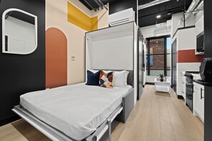 A modern hotel room with a bed, a small kitchenette, and a bathroom with a shower. - Dine, Shop & Explore | Walk to Petco Park & More!! (San Diego)