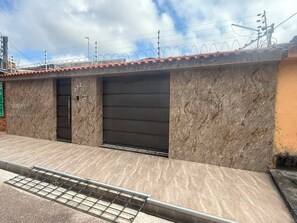 A building with a tiled roof, two garage doors, and a metal grate at the entrance.