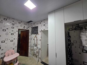 Ein Badezimmer mit weiß gefliesten Wänden, einem Spiegel, einer rosa Wickelmöglichkeit, einem Kleiderschrank und einem Duschbereich.