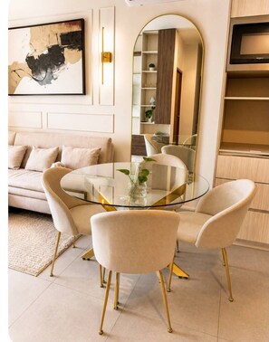 A modern living room with a round glass table, two chairs, a sofa, a large mirror, and a television. - FULLY FURNISHED LOFT, PARKING, GYM, FOUNDRY (Monterrey)