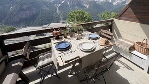 Zona de menjador a l'aire lliure amb taula preparada per a dos, amb vista a un paisatge de muntanyes.