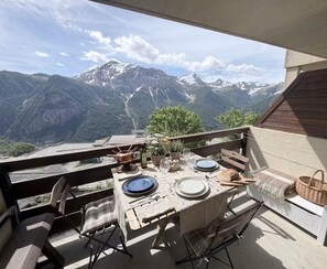 Ein Essbereich im Freien mit einem Tisch für zwei Personen mit Blick auf eine gebirgige Landschaft.