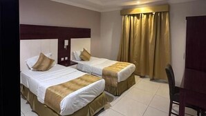 Quarto de hotel com duas camas, uma escrivaninha e uma cadeira.
