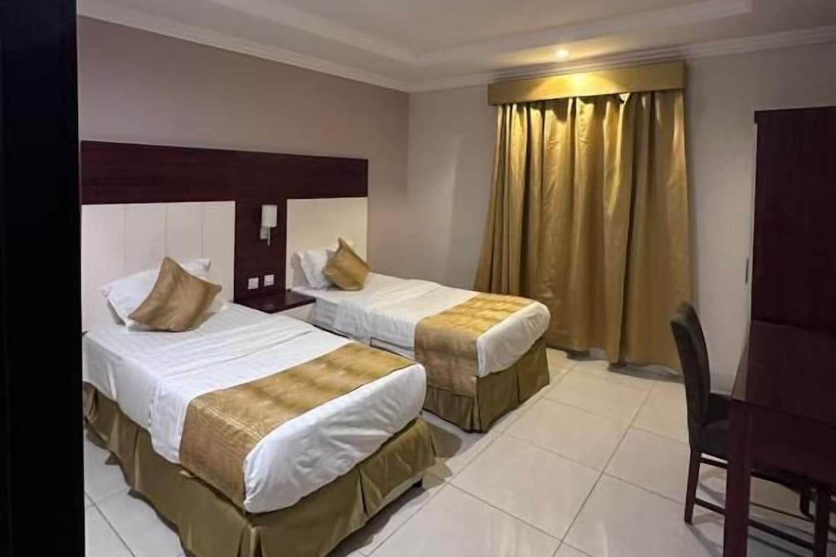 A hotel room with two beds, a desk, and a chair.