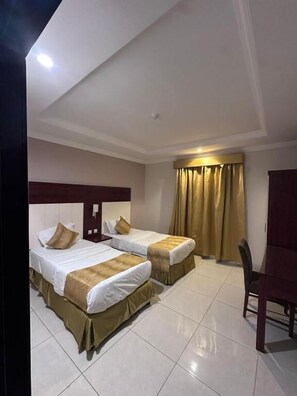 A hotel room with two beds, a desk, and a chair. - Jumeirah Line Serviced Apartments (Jeddah)