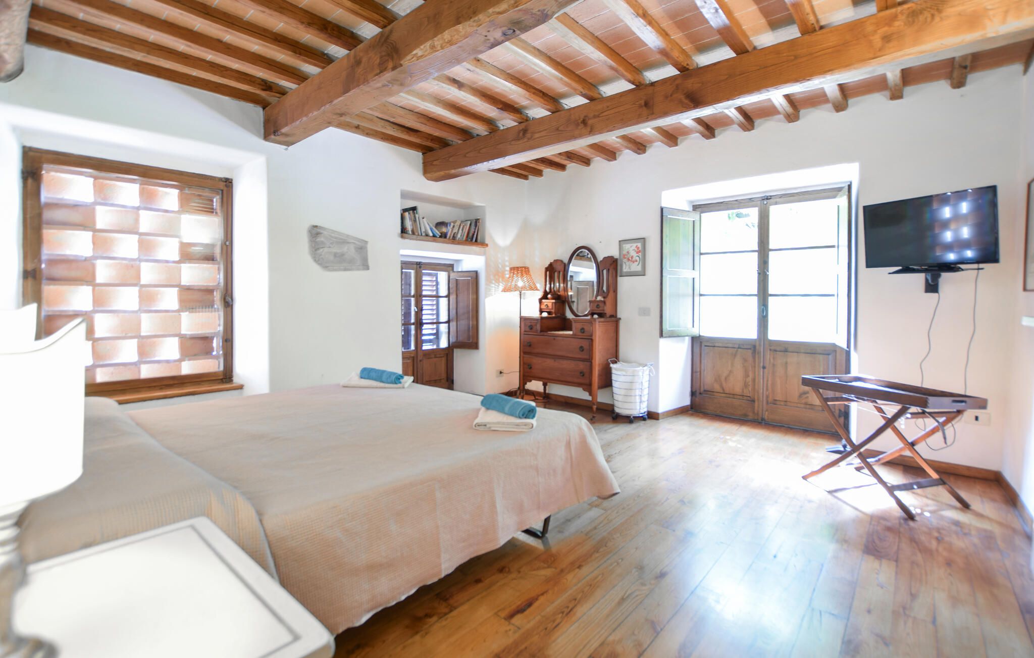A bedroom with a bed, a dresser, a television, and a window with blinds.