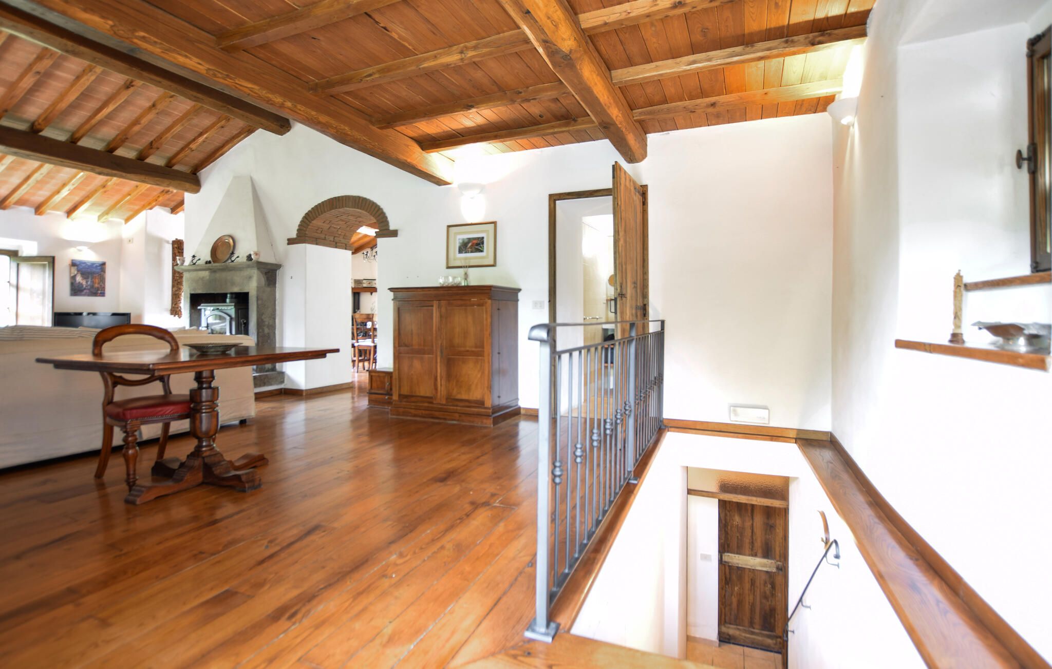 Une pièce spacieuse dotée d’un plancher en bois, d’une cheminée, d’une table à manger avec des chaises et d’un escalier menant à un niveau supérieur.
