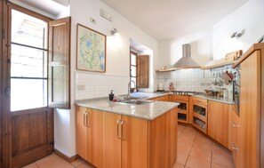 Una cocina con armarios de madera, un lavamanos, una estufa y un mapa en la pared.