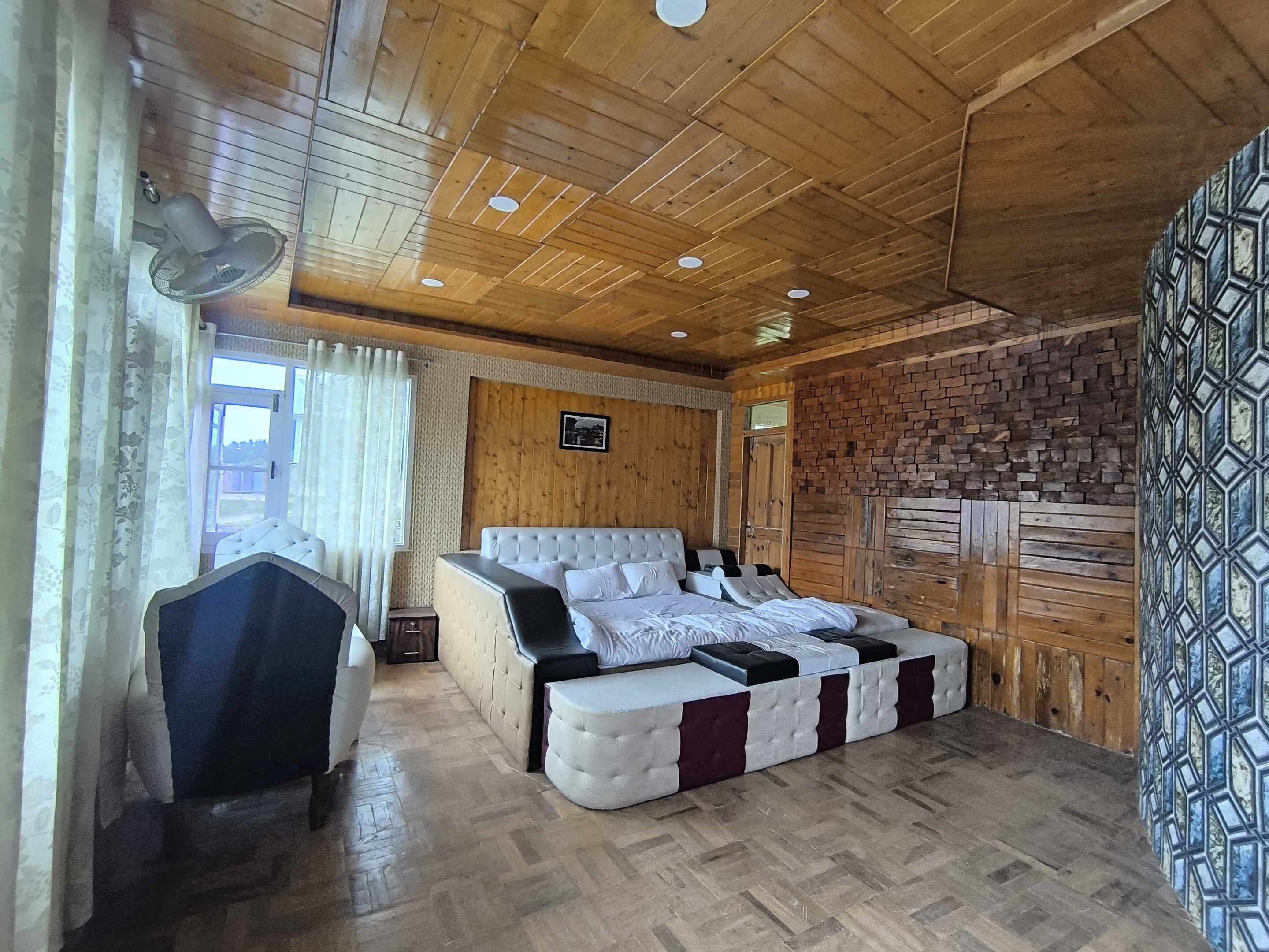 A room with a wooden ceiling, a bed with a headboard, a bedside table, and a patterned wall.