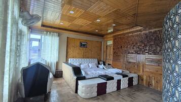 A room with a wooden ceiling, a bed with a headboard, a bedside table, and a patterned wall.