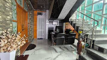 A modern interior with a marble floor, a staircase with metal railings, and a seating area with chairs.