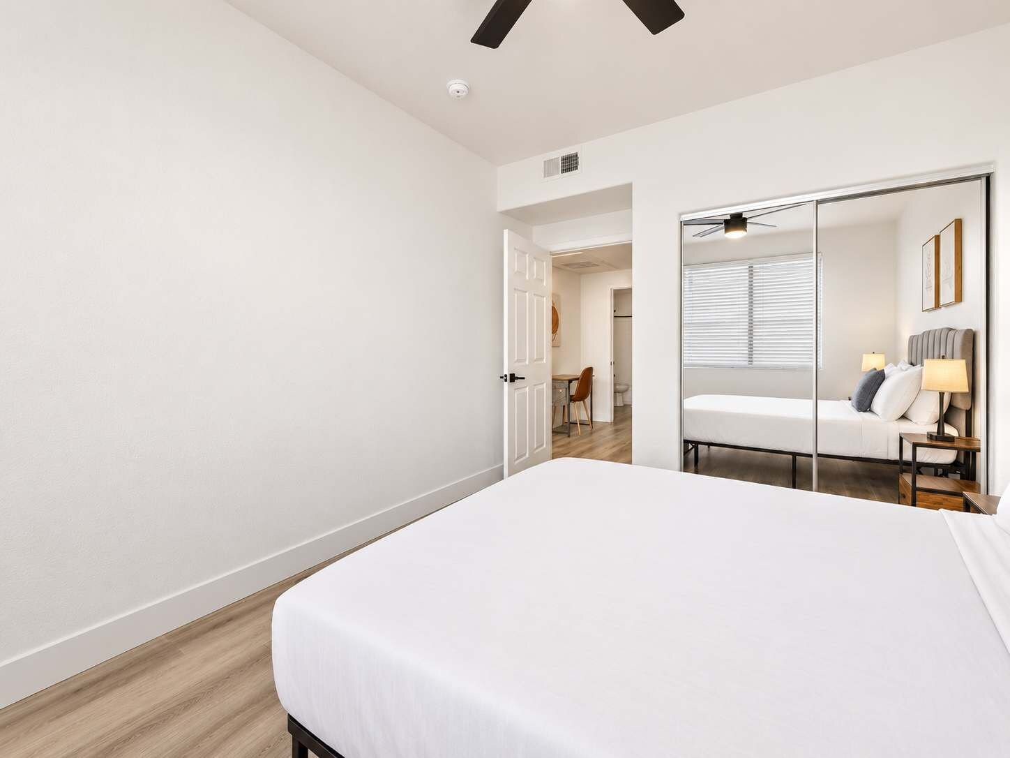Ein modernes Hotelzimmer mit einem großen Bett, einem Spiegel und einer Tür zu einem Badezimmer.