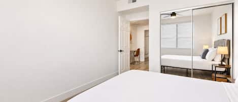 Ein modernes Hotelzimmer mit einem großen Bett, einem Spiegel und einer Tür zu einem Badezimmer.