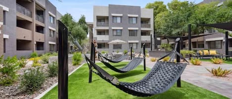 A courtyard with two hammocks, a pool, and a building with balconies.