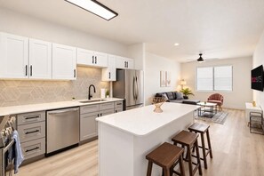 A modern kitchen with white cabinets, a central island, and a dining area with a sofa and chairs. - CozySuites Glendale - Westgate w pool! 1BR 1BA (Glendale)