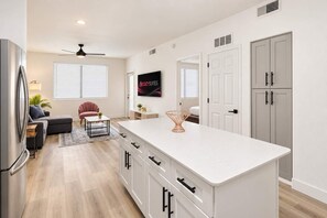 A modern kitchen with a central island, white cabinetry, and a dining area with a sofa and a chair. - CozySuites Glendale - Westgate w pool! 1BR 1BA (Glendale)