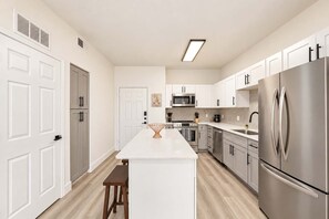 A modern kitchen with white cabinetry, stainless steel appliances, and a central island. - CozySuites Glendale - Westgate w pool! 1BR 1BA (Glendale)