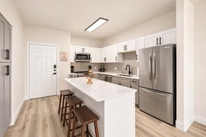 A modern kitchen with white cabinetry, stainless steel appliances, and a central island with stools. - CozySuites Glendale - Westgate w pool! 1BR 1BA (Glendale)