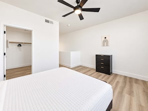 A bedroom with a bed, a wardrobe, a ceiling fan, and a wall-mounted artwork. - CozySuites Glendale - Westgate w pool! 1BR 1BA (Glendale)