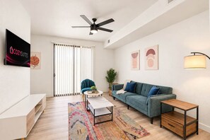 A modern living room with a sofa, coffee table, and a TV. - CozySuites Glendale - Westgate w pool! 1BR 1BA (Glendale)