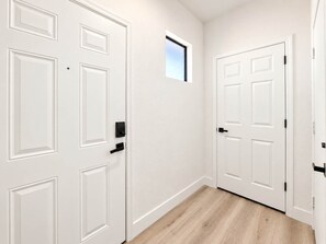 A hallway with white doors, a small window, and wooden flooring. - CozySuites Glendale - Westgate w pool! 1BR 1BA (Glendale)