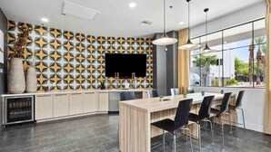 A modern kitchen with a built-in island, a flat-screen TV, and a large window offering a view of the outdoors. - CozySuites Glendale - Westgate w pool! 2BR 2BA (Glendale)