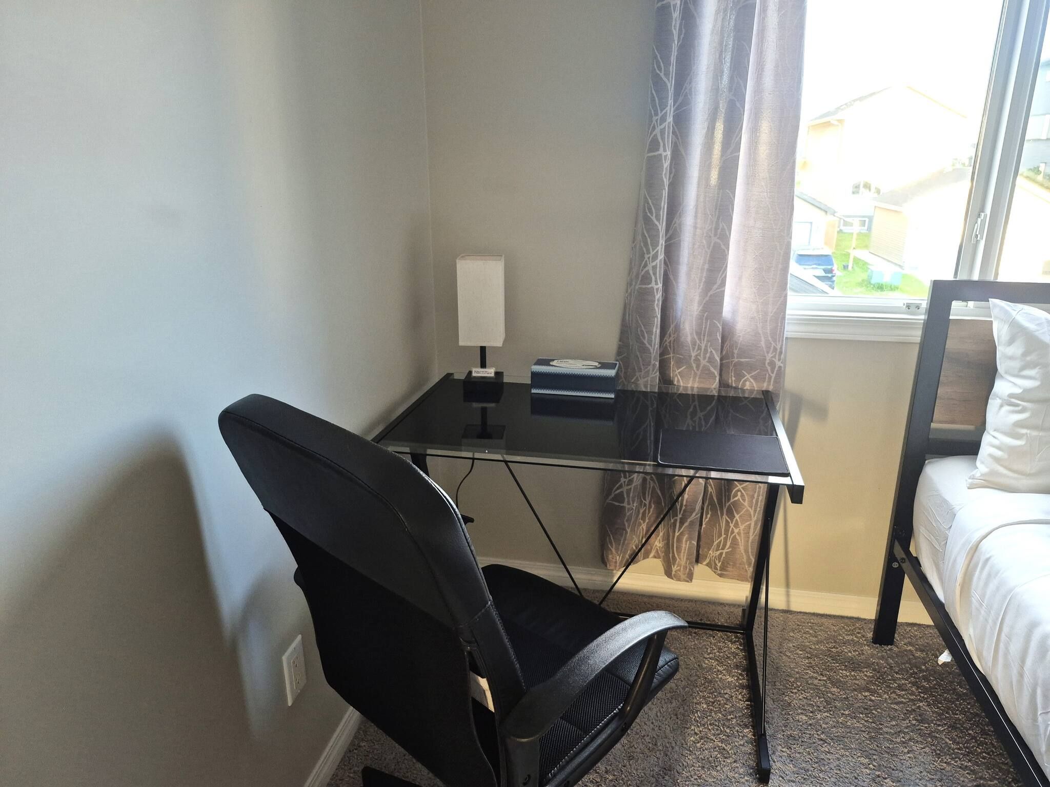 Ein kleines Zimmer mit Schreibtisch, Stuhl und Bett.
