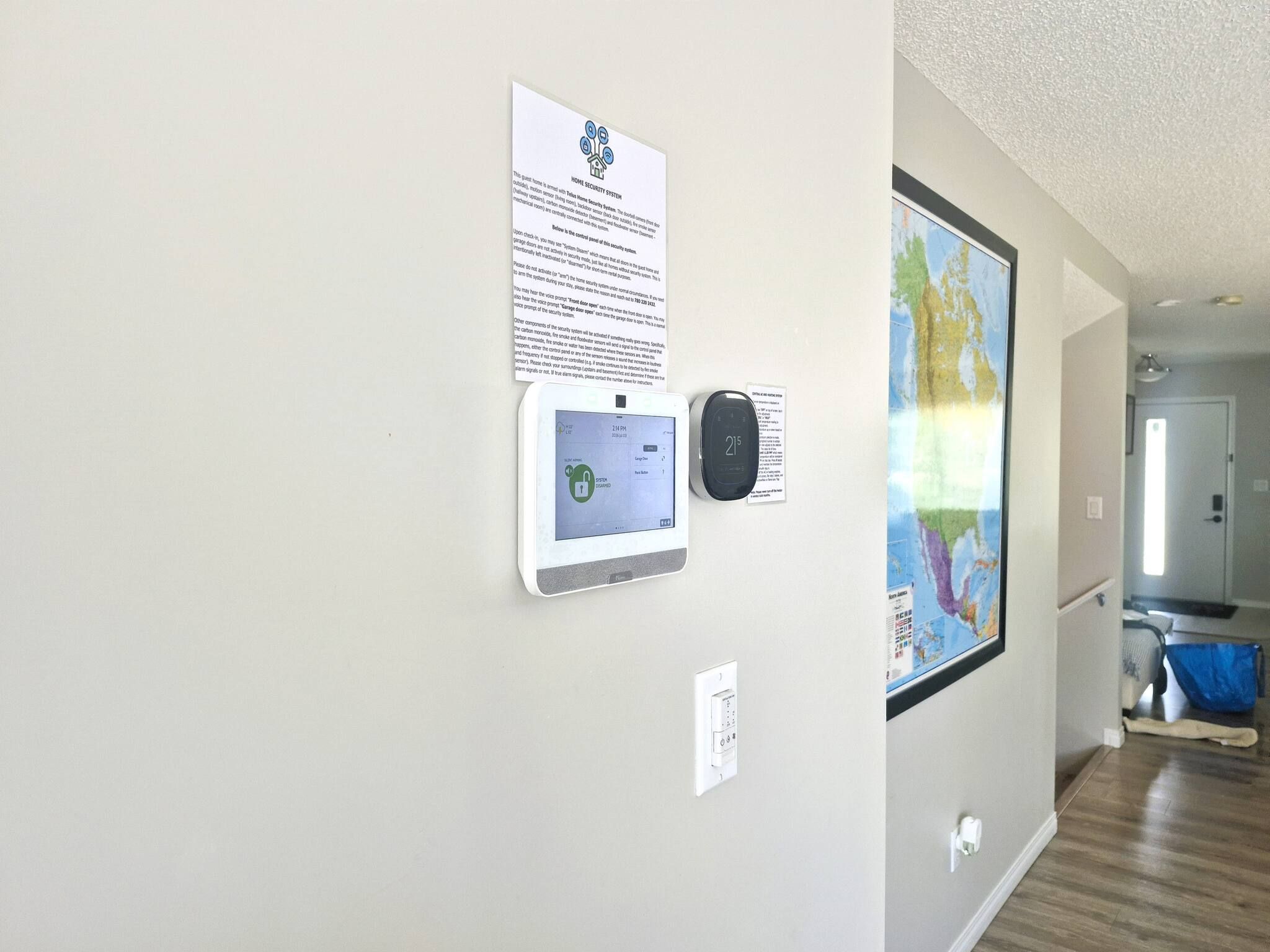 A hallway with a security system sign, a digital clock, and a map on the wall.