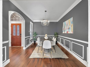 A dining area with a chandelier, a dining table, chairs, and a rug. - Modern & Cozy 3BR Home Close to Lake (Grand Prairie)